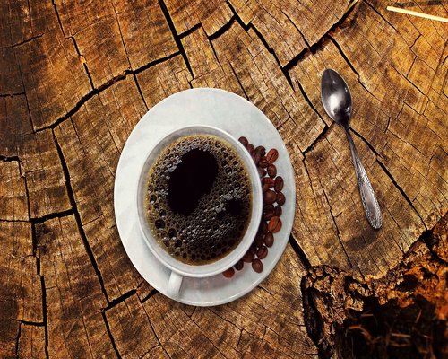 A cup of coffee on a table with morning sunlight coming through window