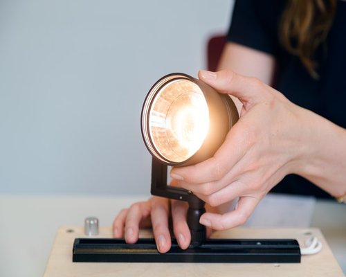 Person adjusting light intensity on a desk lamp